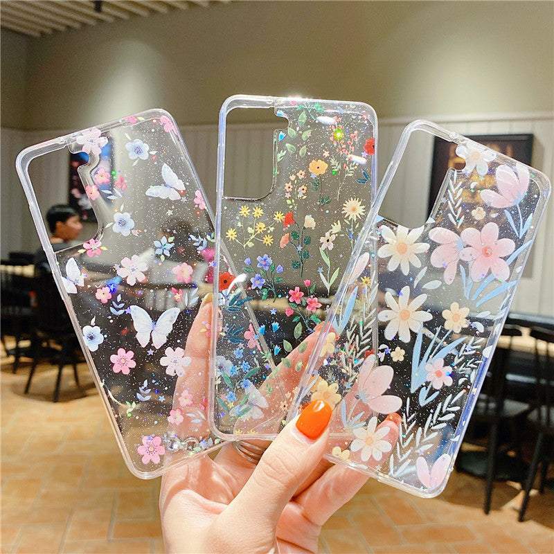 Three fashion minimalist floral TPU phone cases with colorful flower and butterfly designs on transparent backgrounds held in hand