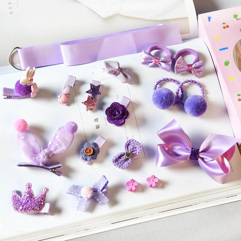 Purple girls hair accessories set with bows, clips, and pom-poms on a book background